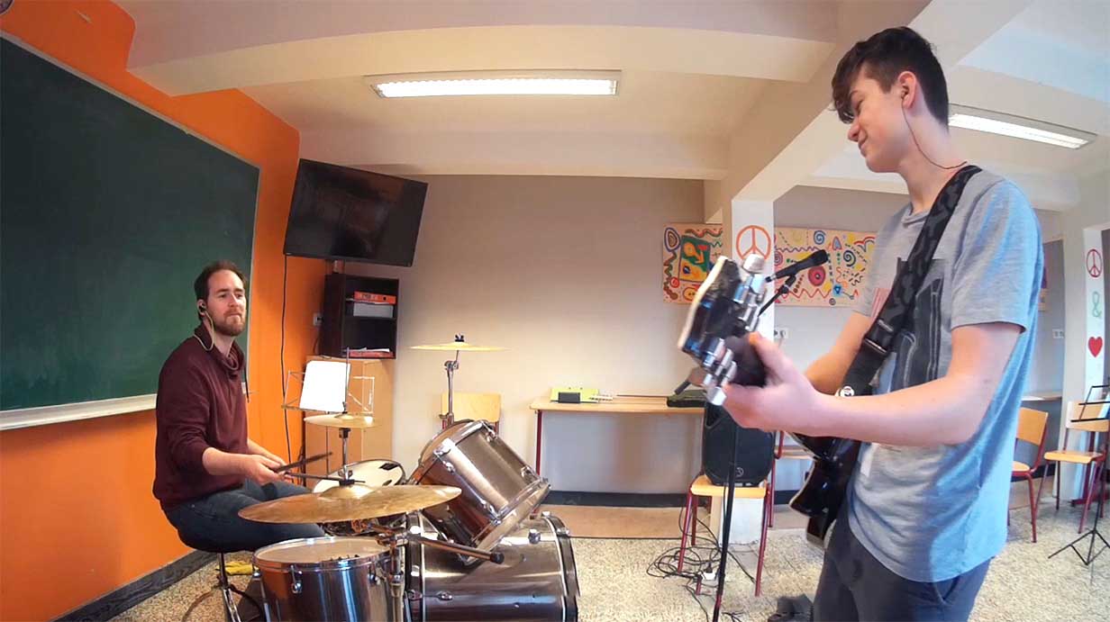 Professeur de musique qui accompagne son élève guitariste à la batterie