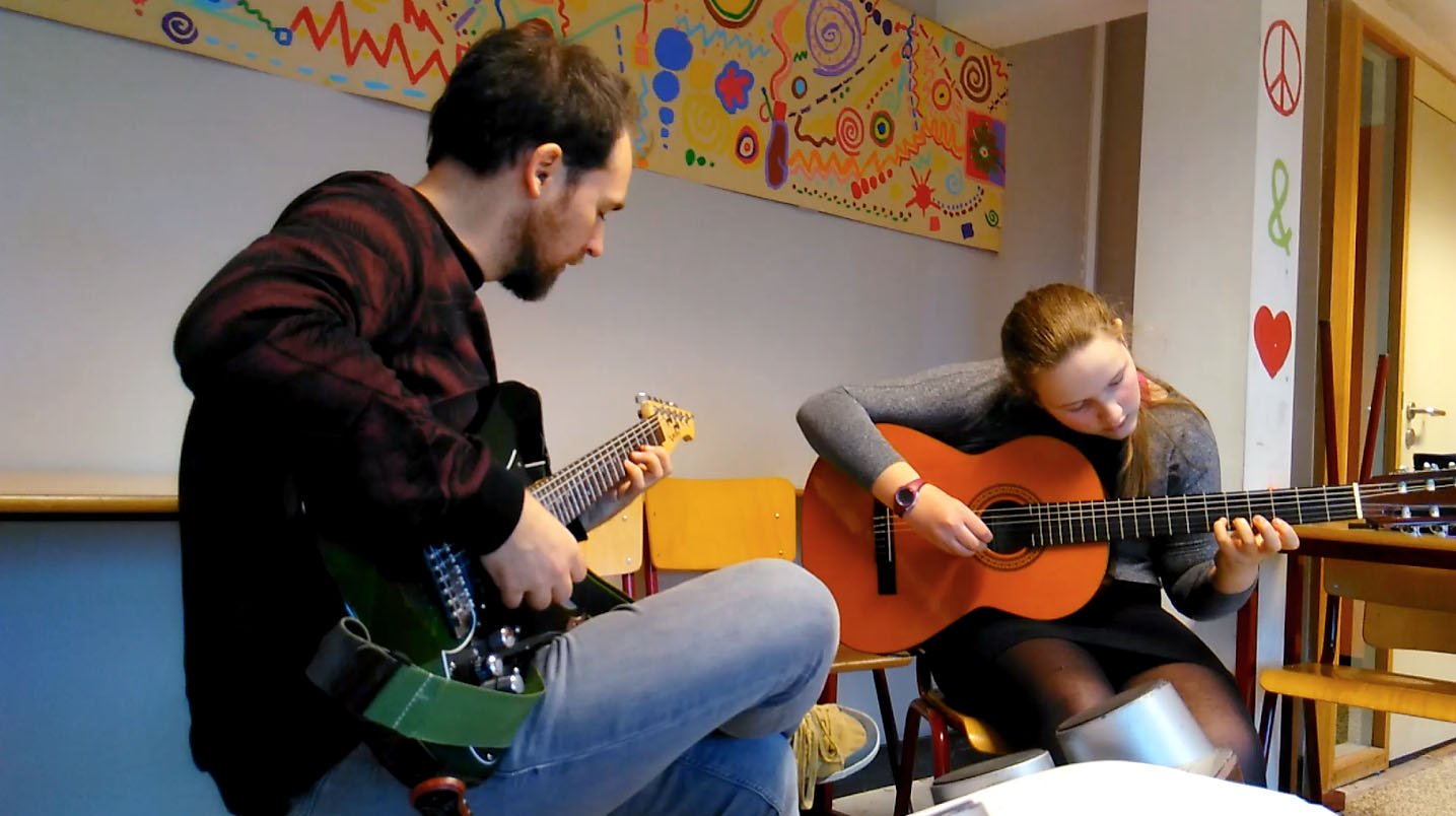 fille adolescente qui apprend à jouer de la guitare avec son professeur