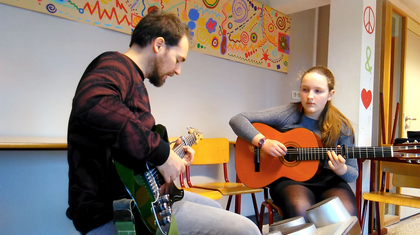 fille adolescente qui apprend à jouer de la guitare avec son professeur